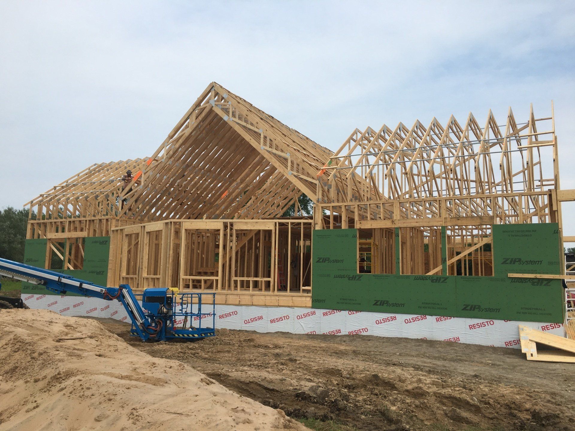 Framing of a house under construction with exposed wooden trusses and green sheathing panels
