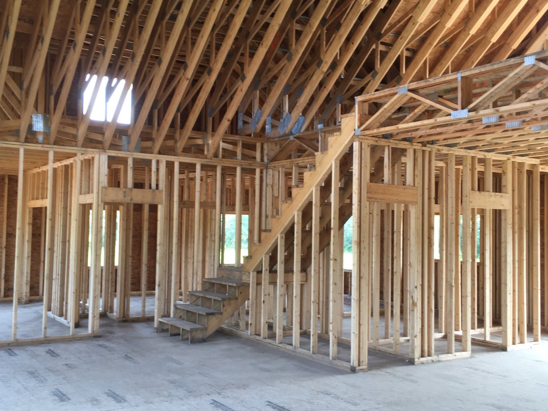 Interior of a wooden house frame under construction with exposed roof trusses and stairs