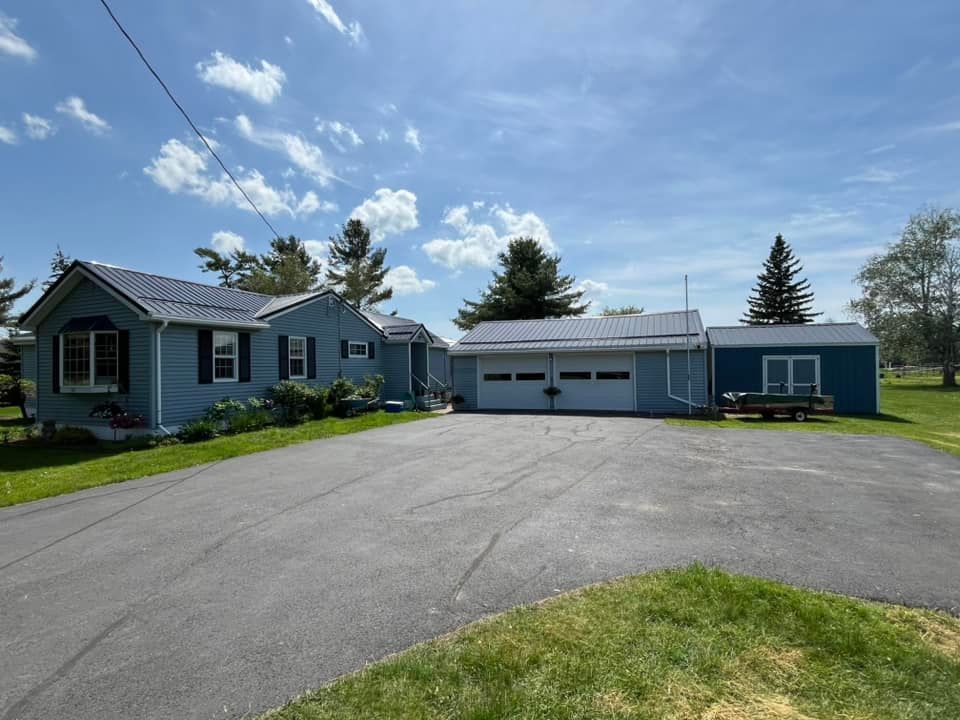 A blue house with a garage and a driveway in front of it