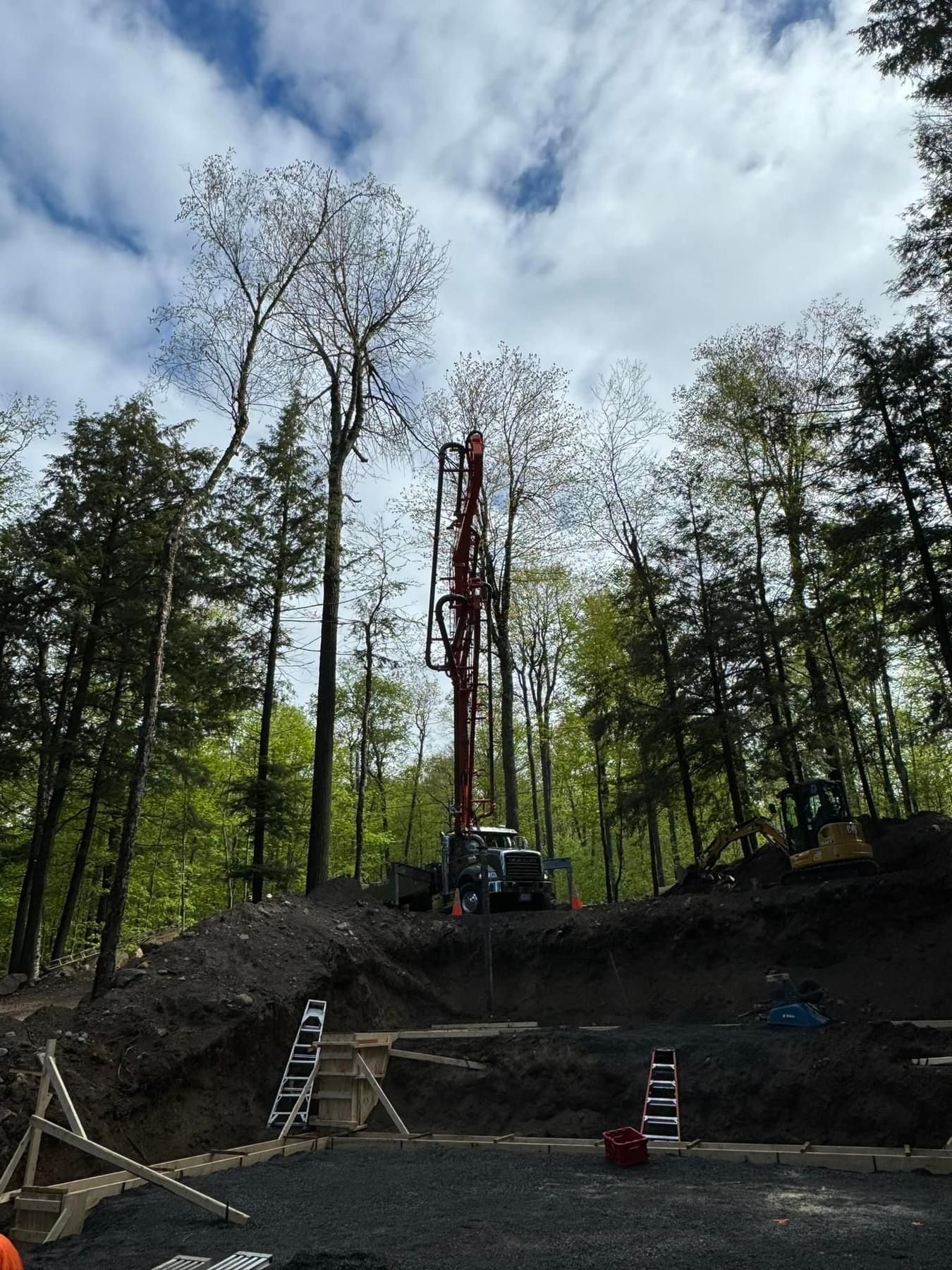Tree removal worksite with a crane lifting a tall tree trunk above a forested slope