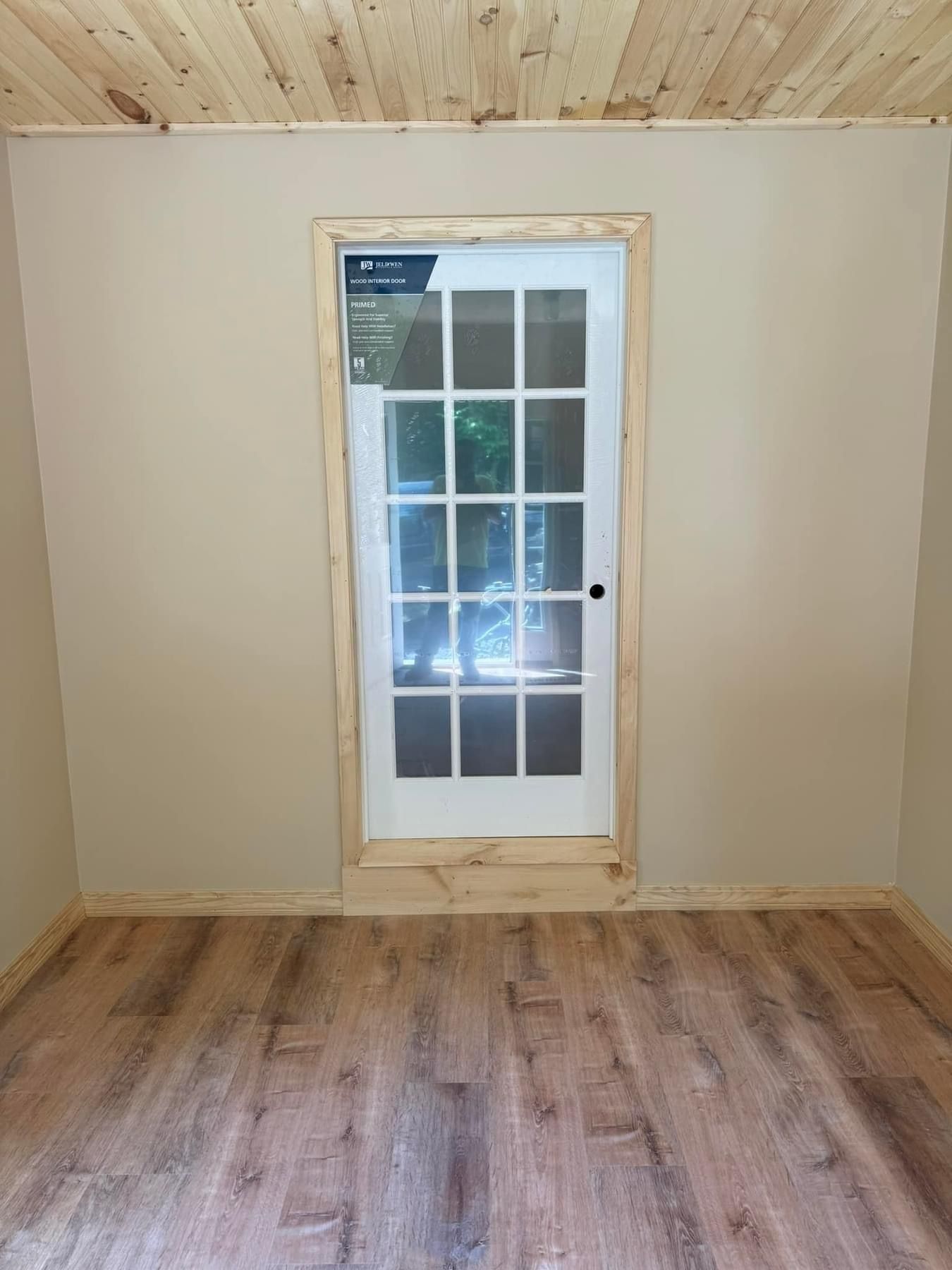 Empty room with wood floor, light walls, and a glass French door centered on the far wall.