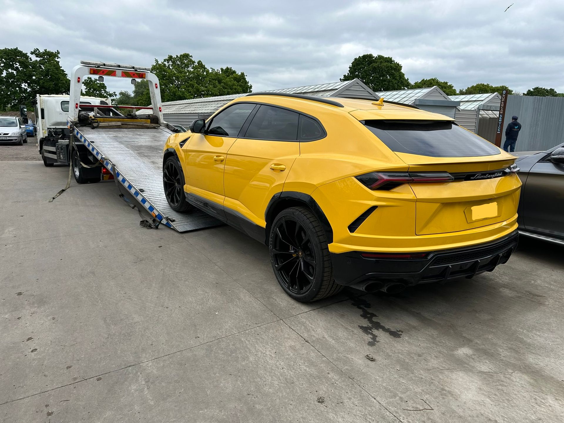 A yellow lamborghini urus is being towed by a tow truck.