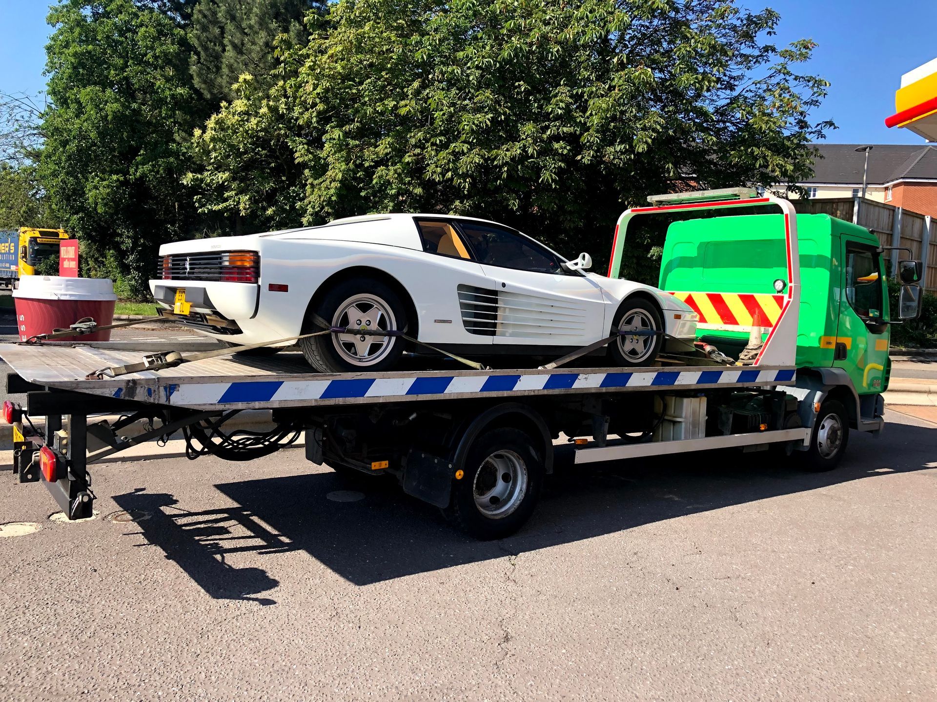 A white sports car is being towed by a tow truck.