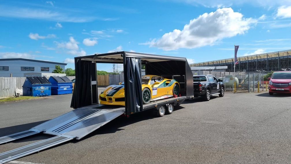 A yellow sports car is being transported on a trailer.