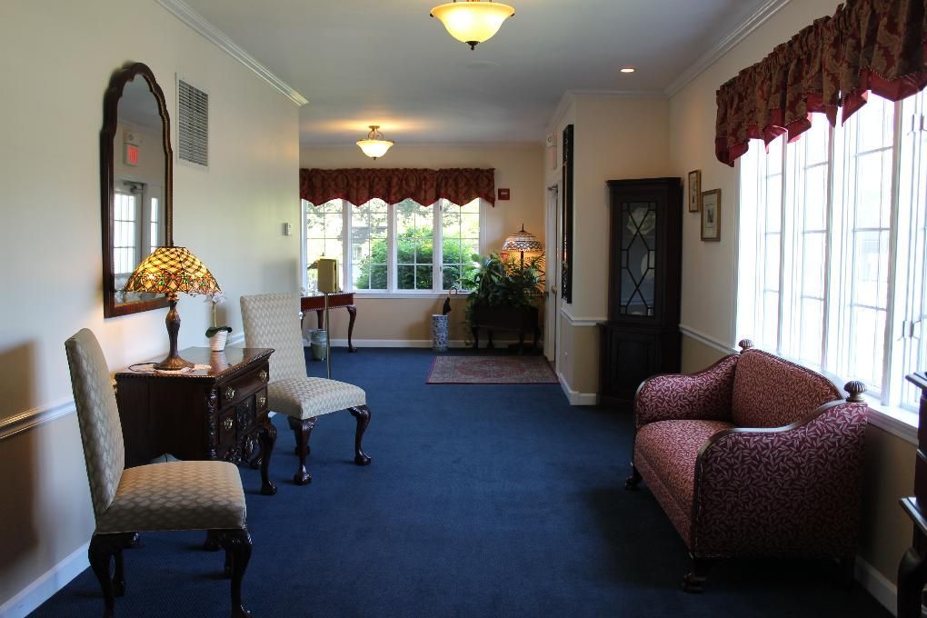 Bright waiting room with blue carpet, red chairs, and large windows with curtains