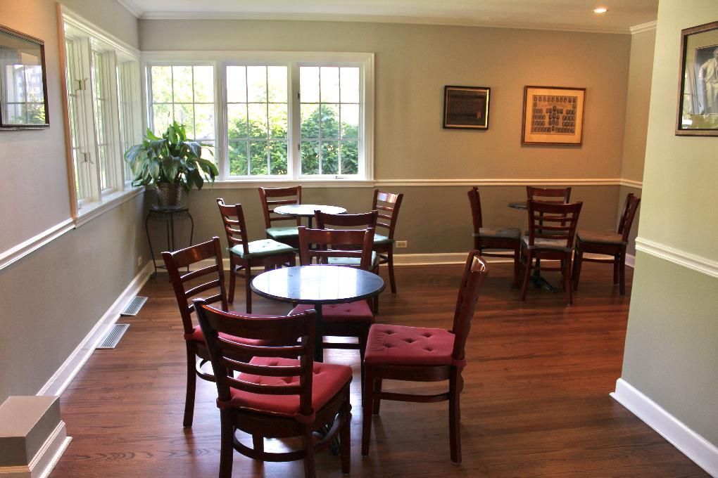 Empty dining room with wooden tables and chairs, hardwood floor, and large windows letting in daylight