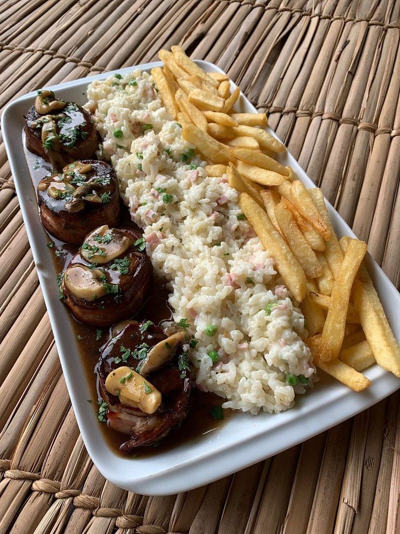 Um prato de comida com batatas fritas e risoto sobre uma mesa.