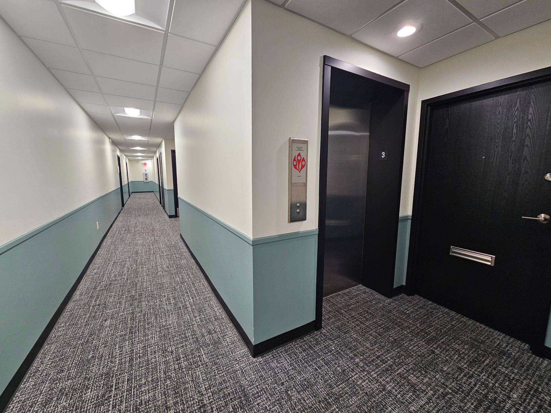 A long hallway with a elevator in the middle of it.