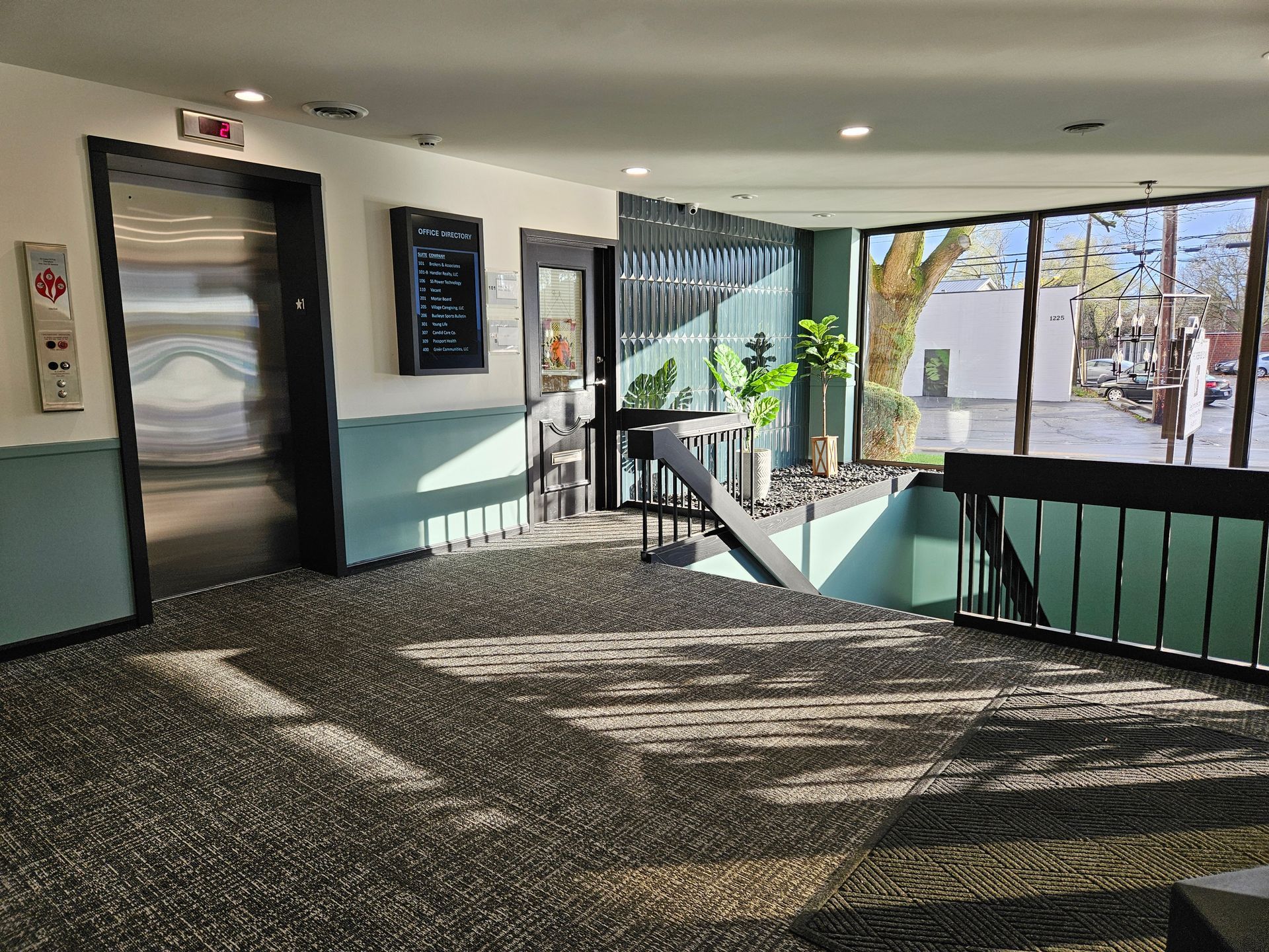 A hallway with a staircase and an elevator in a building.
