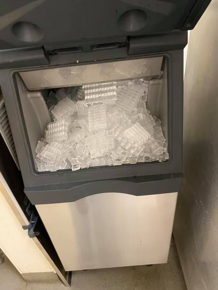 A stainless steel ice maker filled with ice cubes.