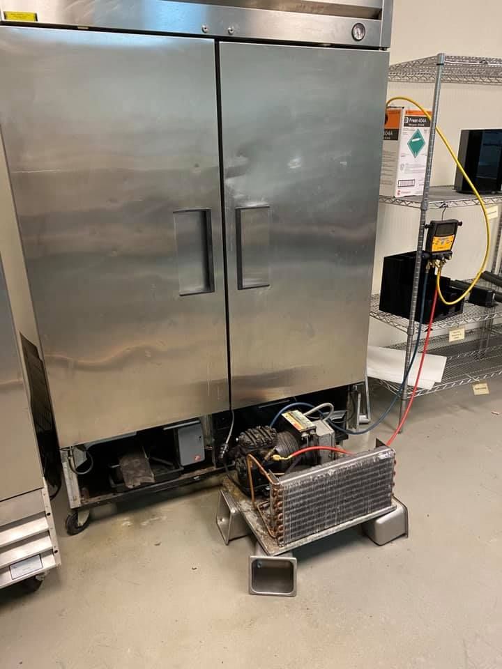 A stainless steel refrigerator with the door open is sitting on the floor in a kitchen.