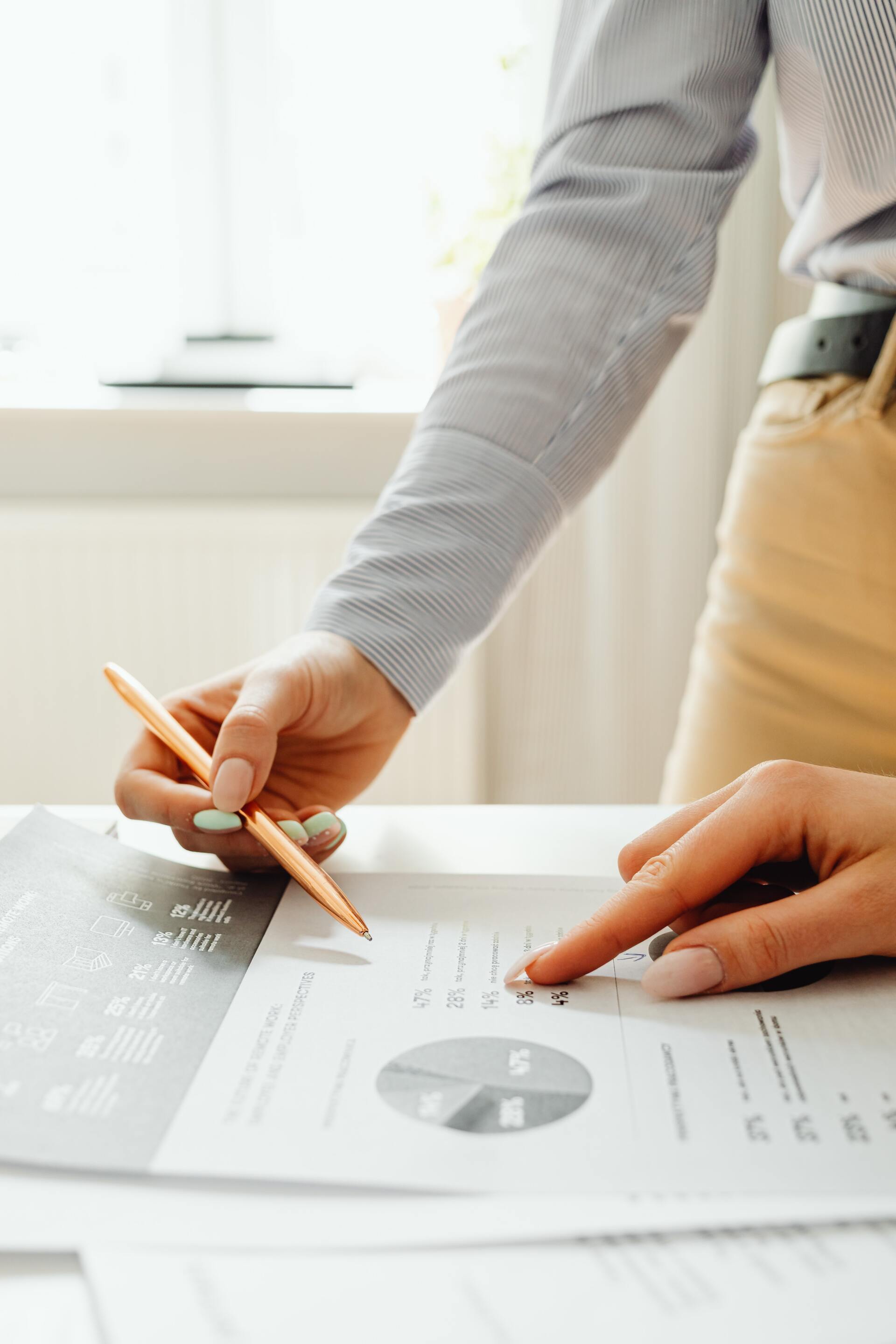Une personne tient un crayon et pointe un graphique sur une feuille de papier.