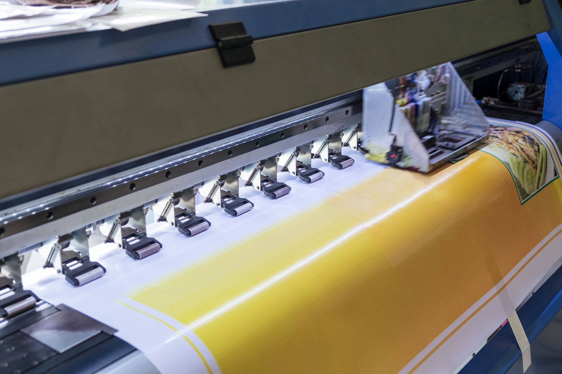 Large format printer printing a yellow banner, with ink cartridges in operation.