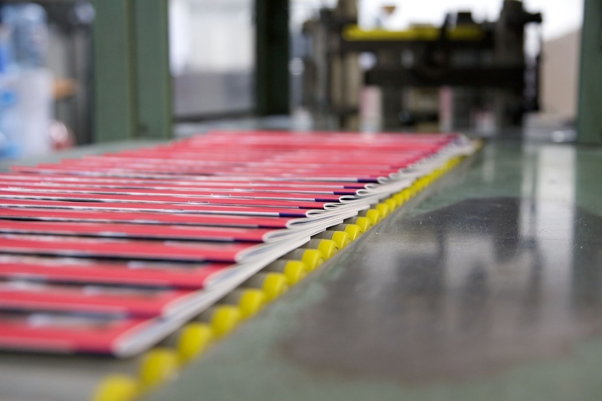 Red magazines on a conveyor belt in a printing factory.