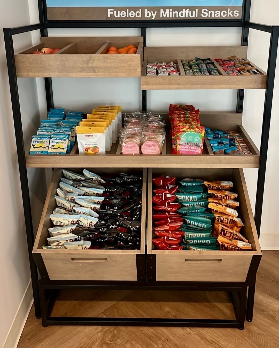 Snack display shelf stocked with assorted granola bars and treats, labeled “Fueled by Mindful Snacks”