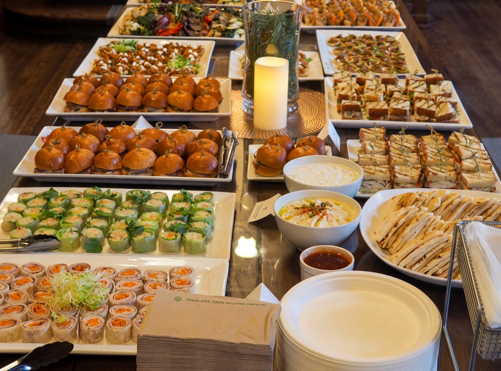 Buffet table with assorted appetizers, desserts, and a lit candle centerpiece