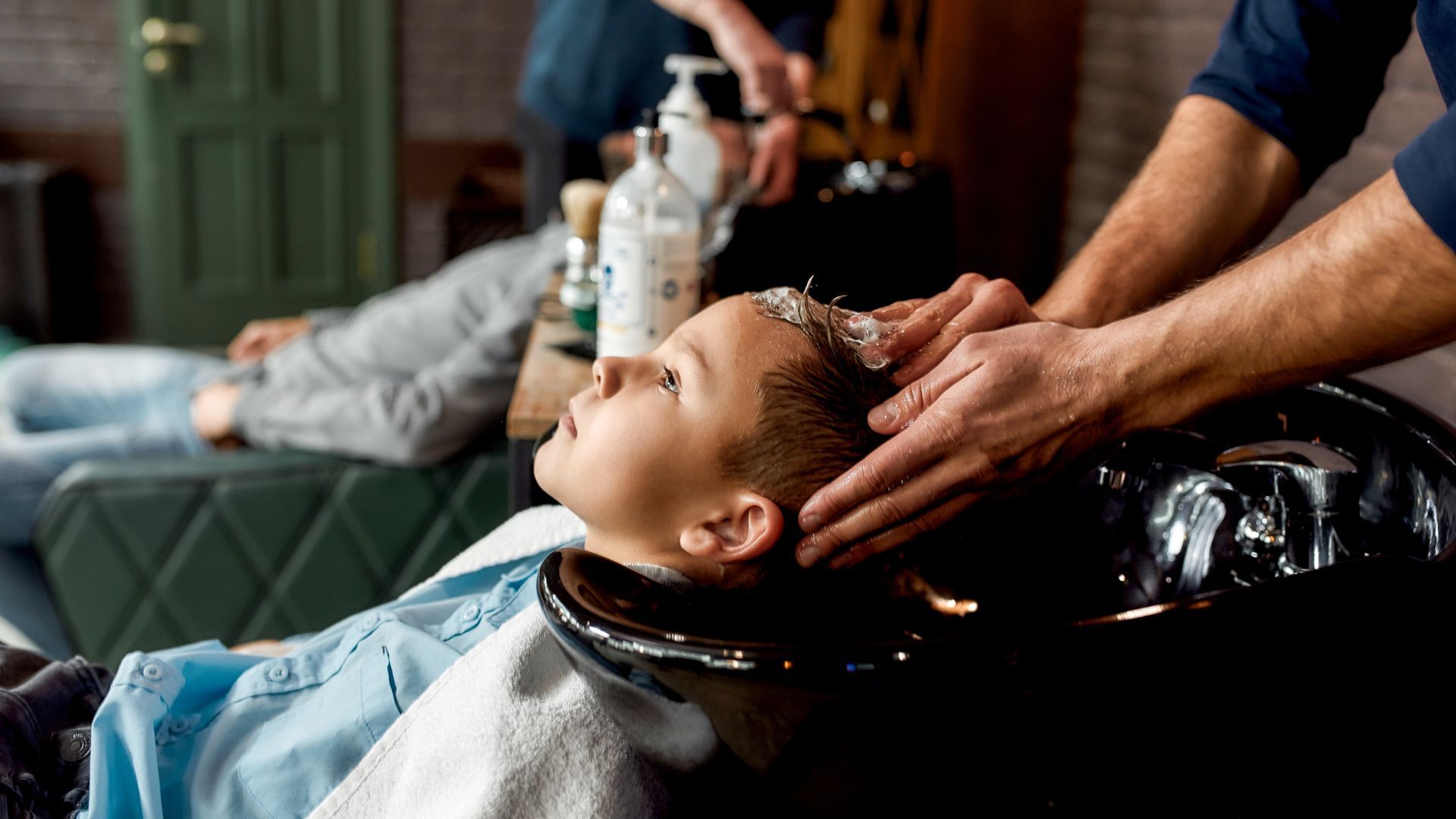 Person getting a shampoo at a salon sink while another person massages their scalp