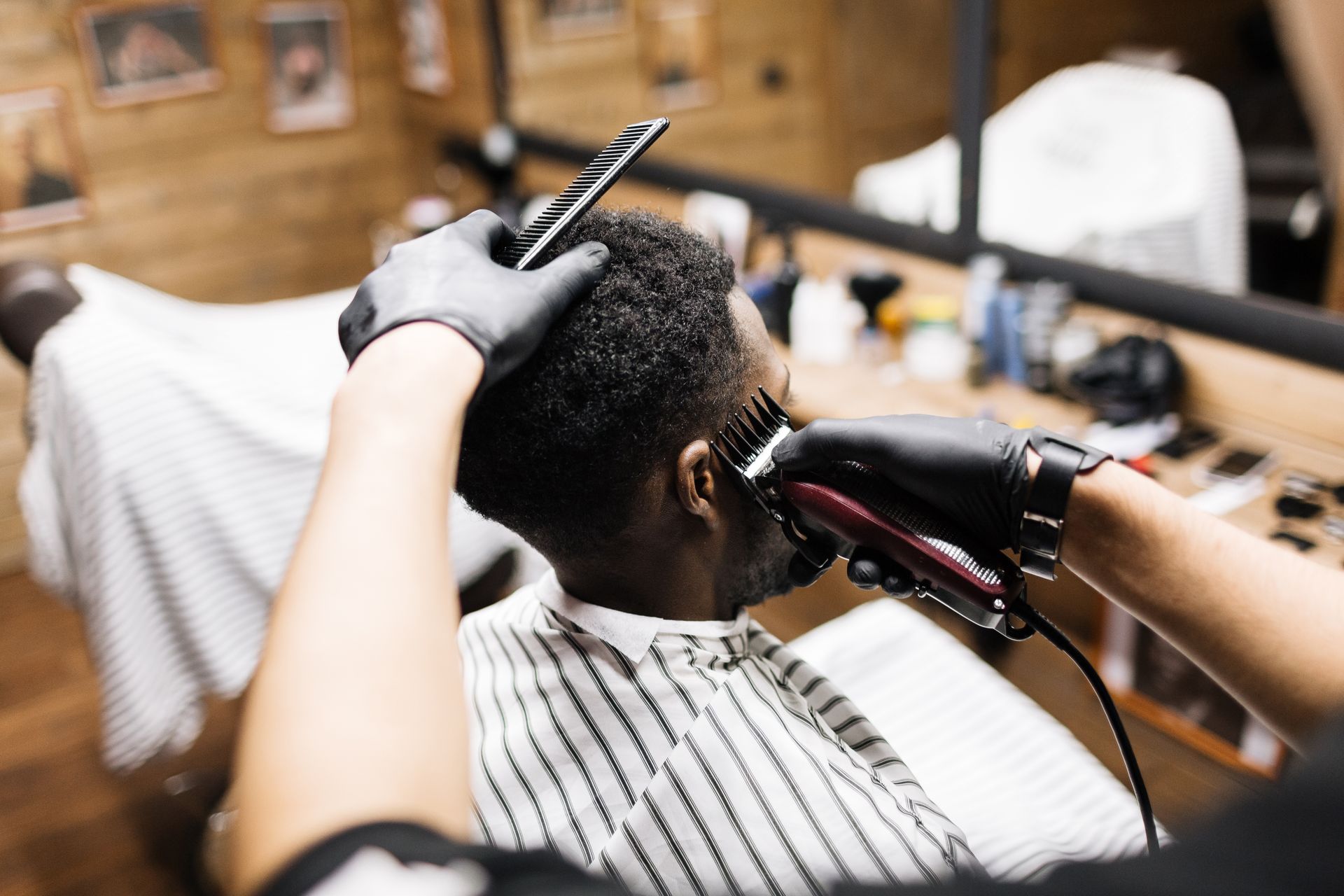 Person getting a haircut in a barbershop, with clippers and a comb visible.