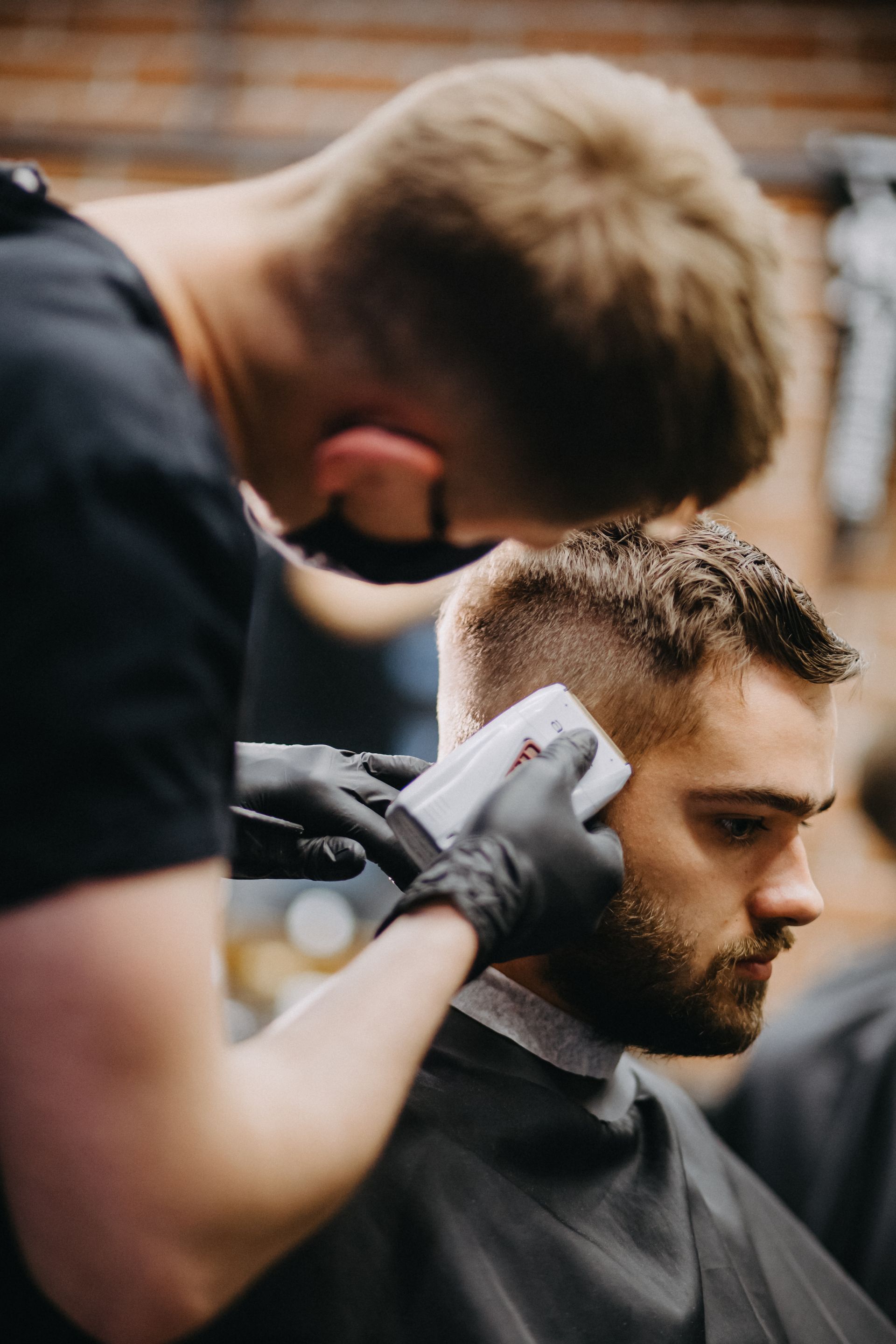 Barber trimming a man’s hair with clippers in a salon