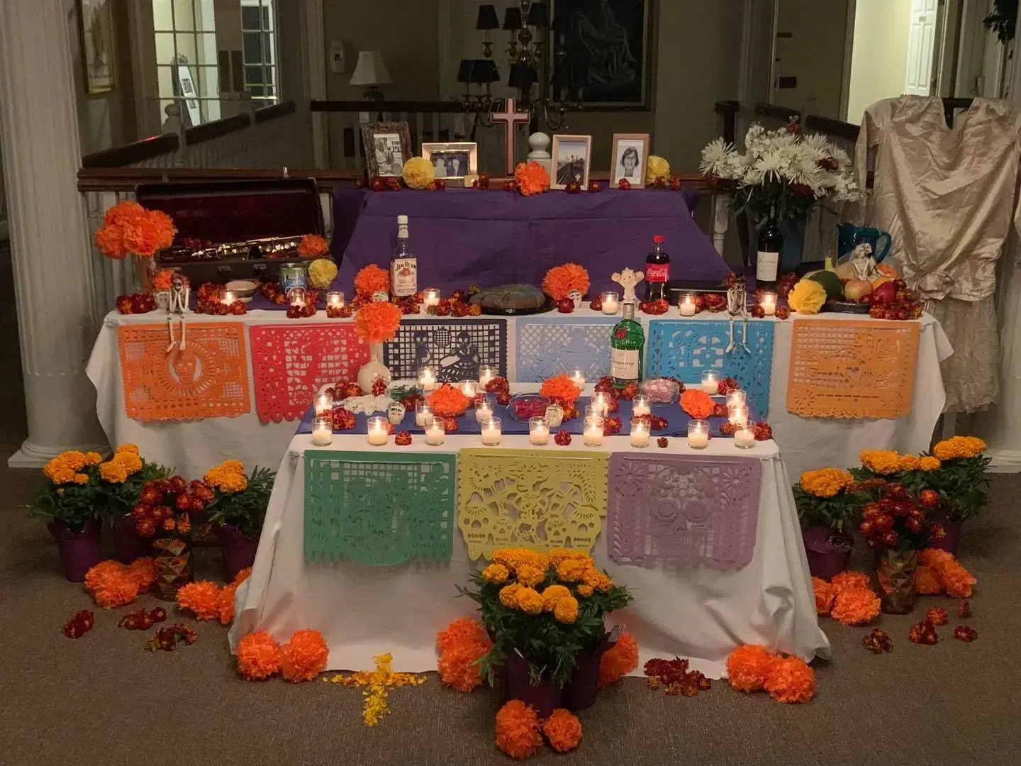 Colorful Dia de los Muertos altar with marigolds, candles, photos, and decorated offerings