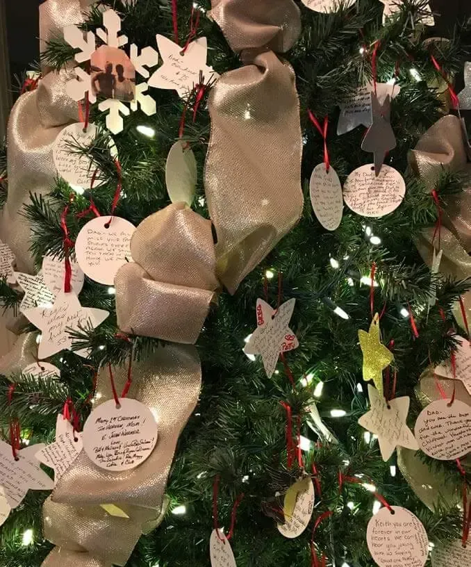 Christmas tree with gold ribbon garland and hanging paper ornaments on green branches
