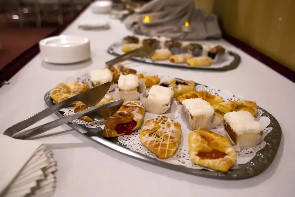 Dessert platter with sliced fruit, whipped cream, and tongs on a dining table