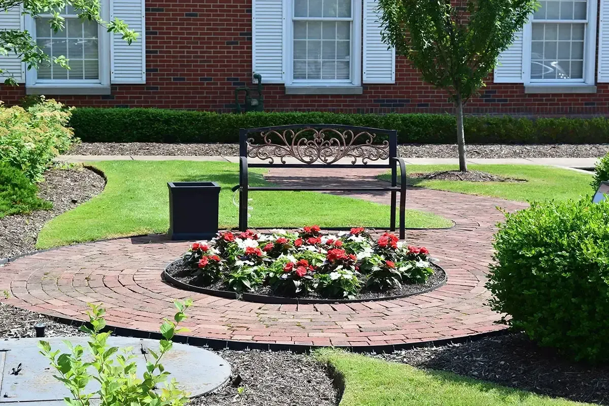 Brick courtyard with a bench and flowerbed in front of a brick building