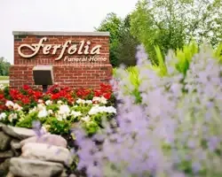 Ferfolia Funeral Home sign amid colorful flowers and greenery