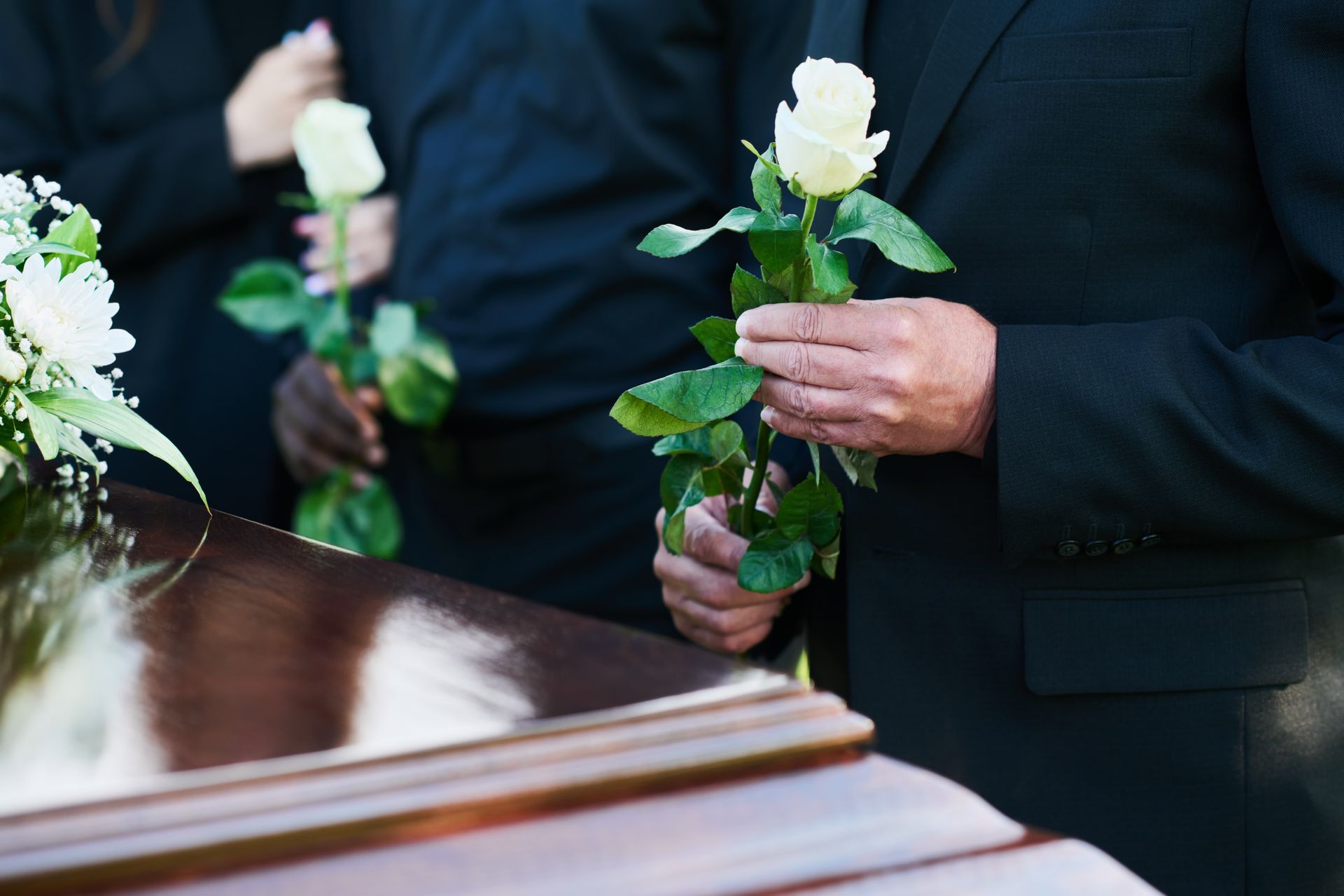 A man in a suit is sitting at a coffin at a funeral.