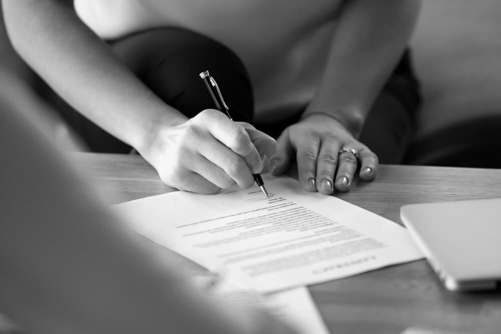 Woman Signing Documents With Black And Golden Coloured Pen — Farrell Lusher Solicitors In Wagga Wagga, NSW