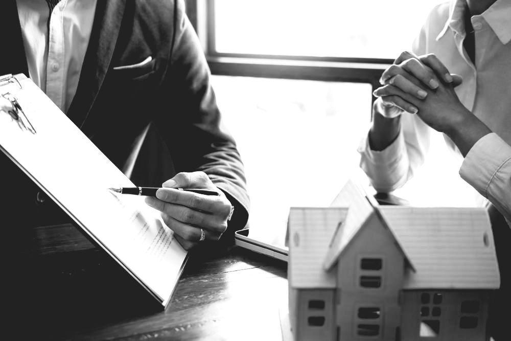 A Man And A Woman Are Shaking Hands In An Office — Farrell Lusher Solicitors In Wagga Wagga, NSW