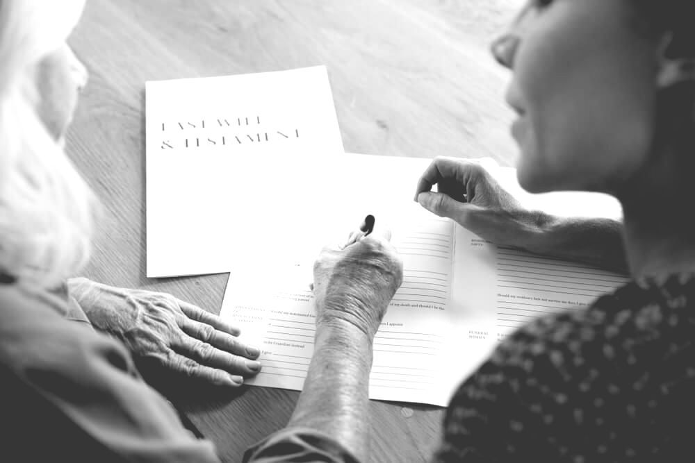 Woman Is Signing A Last Will And Testament And Other Women Guiding Her — Farrell Lusher Solicitors In Wagga Wagga, NSW