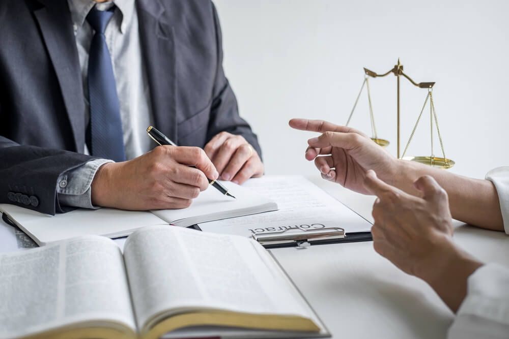 A Man Is Writing In A Notebook And A Document Below It On A Clipboard With The Word — Farrell Lusher Solicitors In Wagga Wagga, NSW