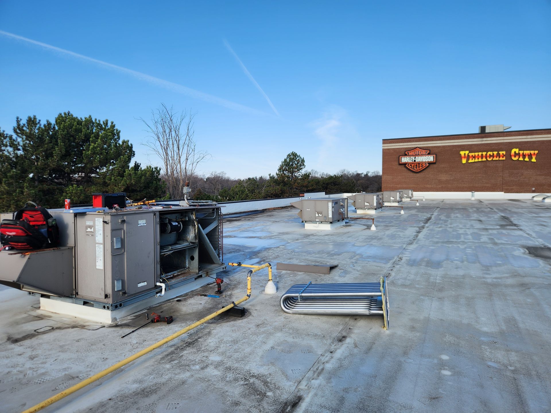 Rooftop with HVAC units; a Harley Davidson shop is in the background. Bright, sunny day.