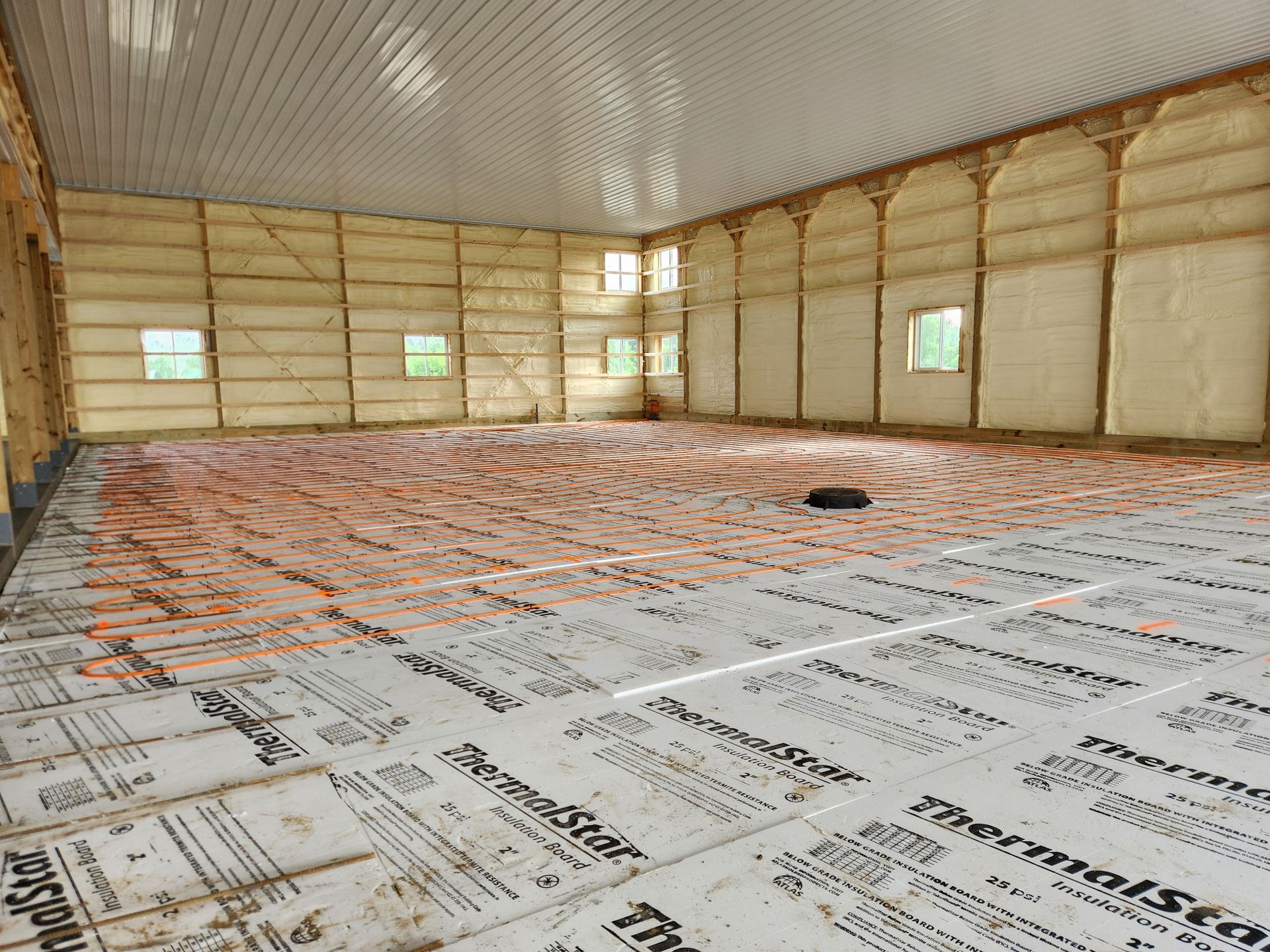 Interior view of a building under construction, featuring insulation on walls and floor. 