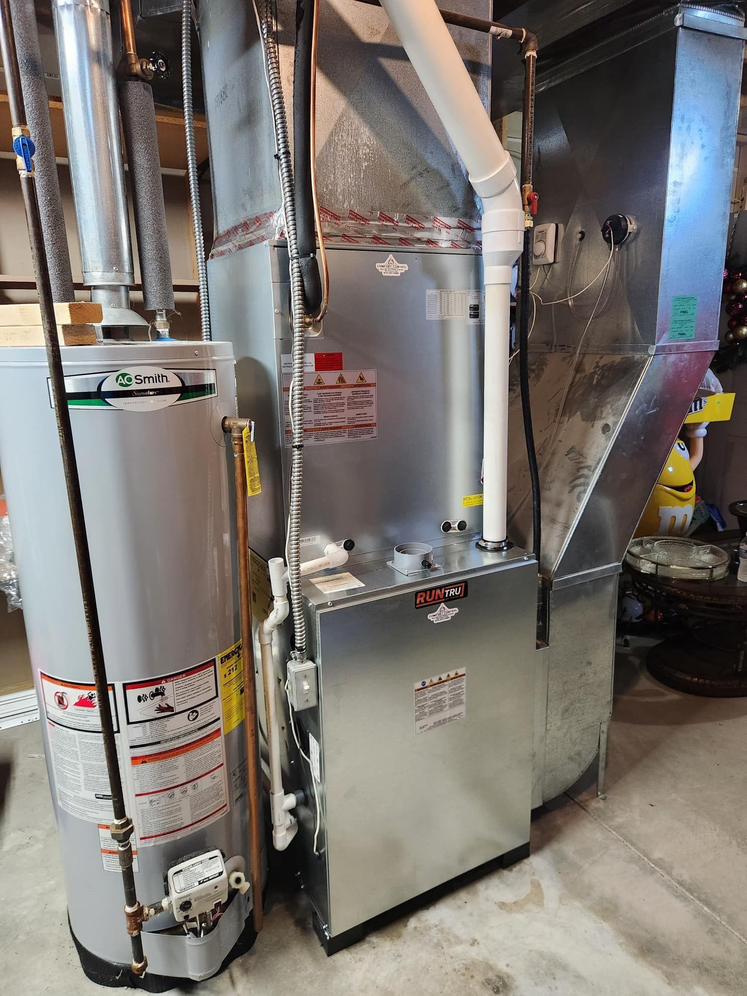 A gas water heater and furnace unit in a basement setting.