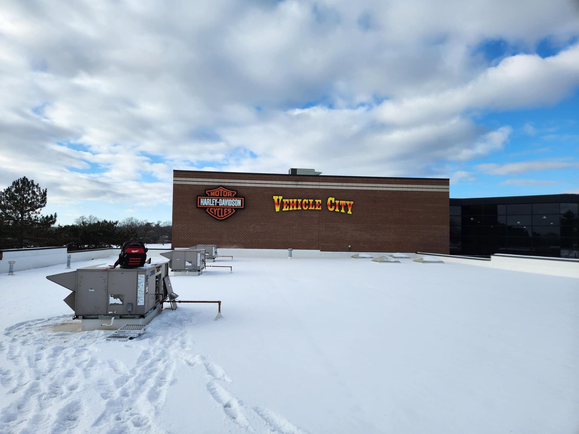 Snowy rooftop view of a Harley-Davidson dealership in Temple City. The sky is cloudy and blue.