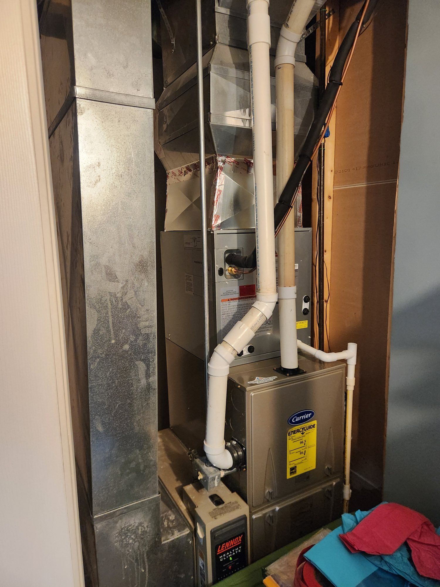 Furnace in a basement; metal ductwork, PVC pipes, and a control panel are visible.
