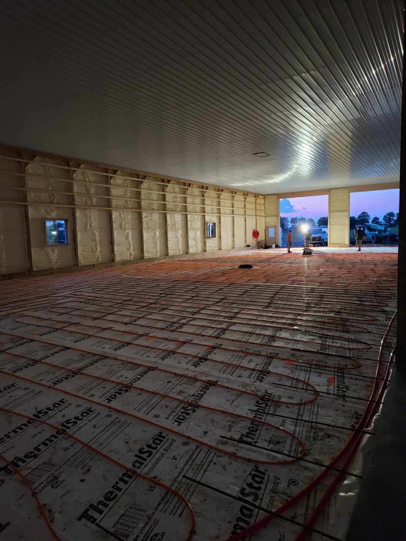 Interior view of a building under construction, featuring radiant floor heating, open walls, and a curved ceiling.