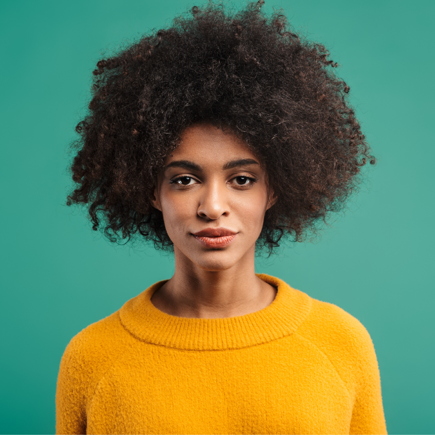 A woman is wearing a yellow sweater and looking at the camera.