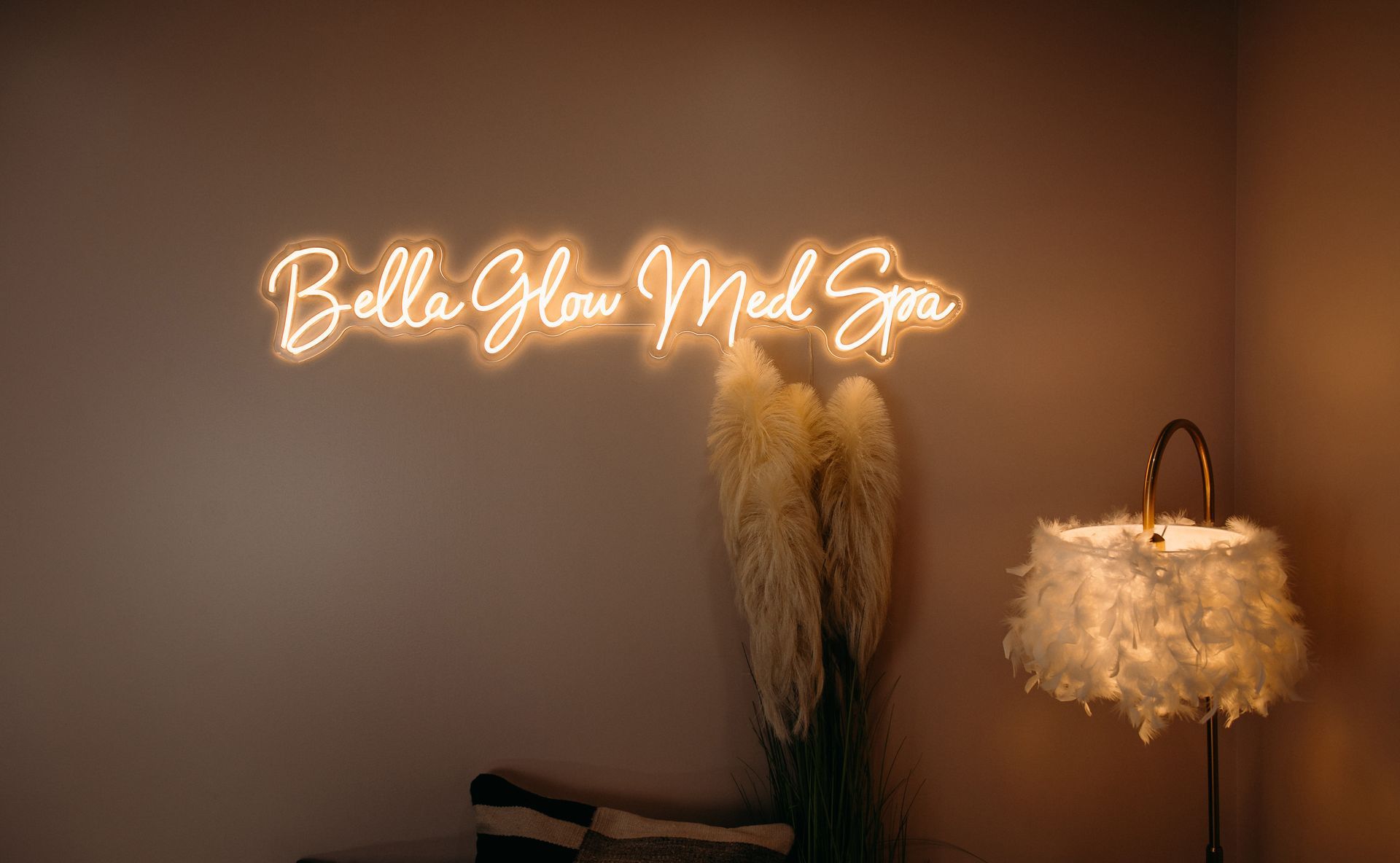 There is a neon sign on the wall that says bella glow med spa.