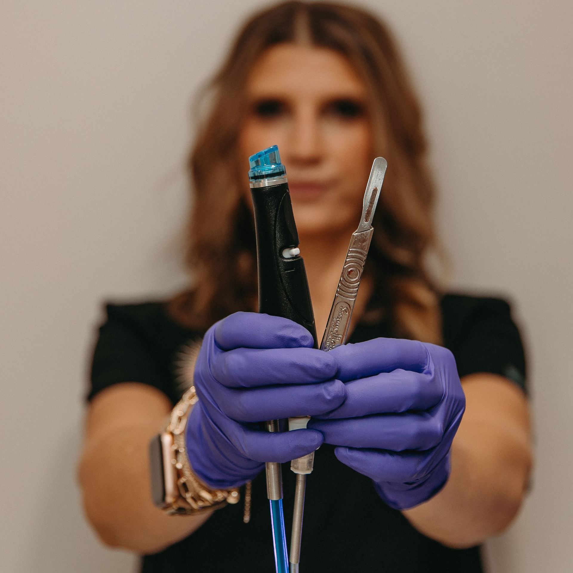 A woman wearing purple gloves is holding a pen and a syringe.