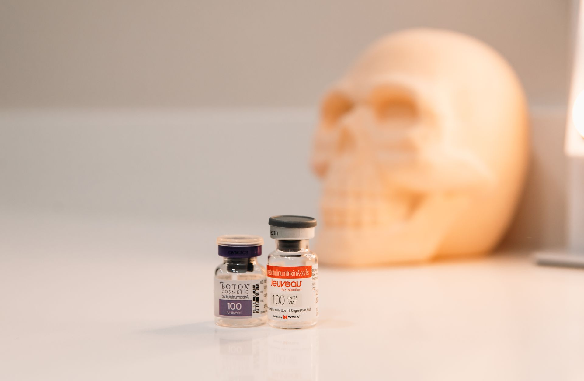 Two bottles of pills are sitting on a table in front of a skull.