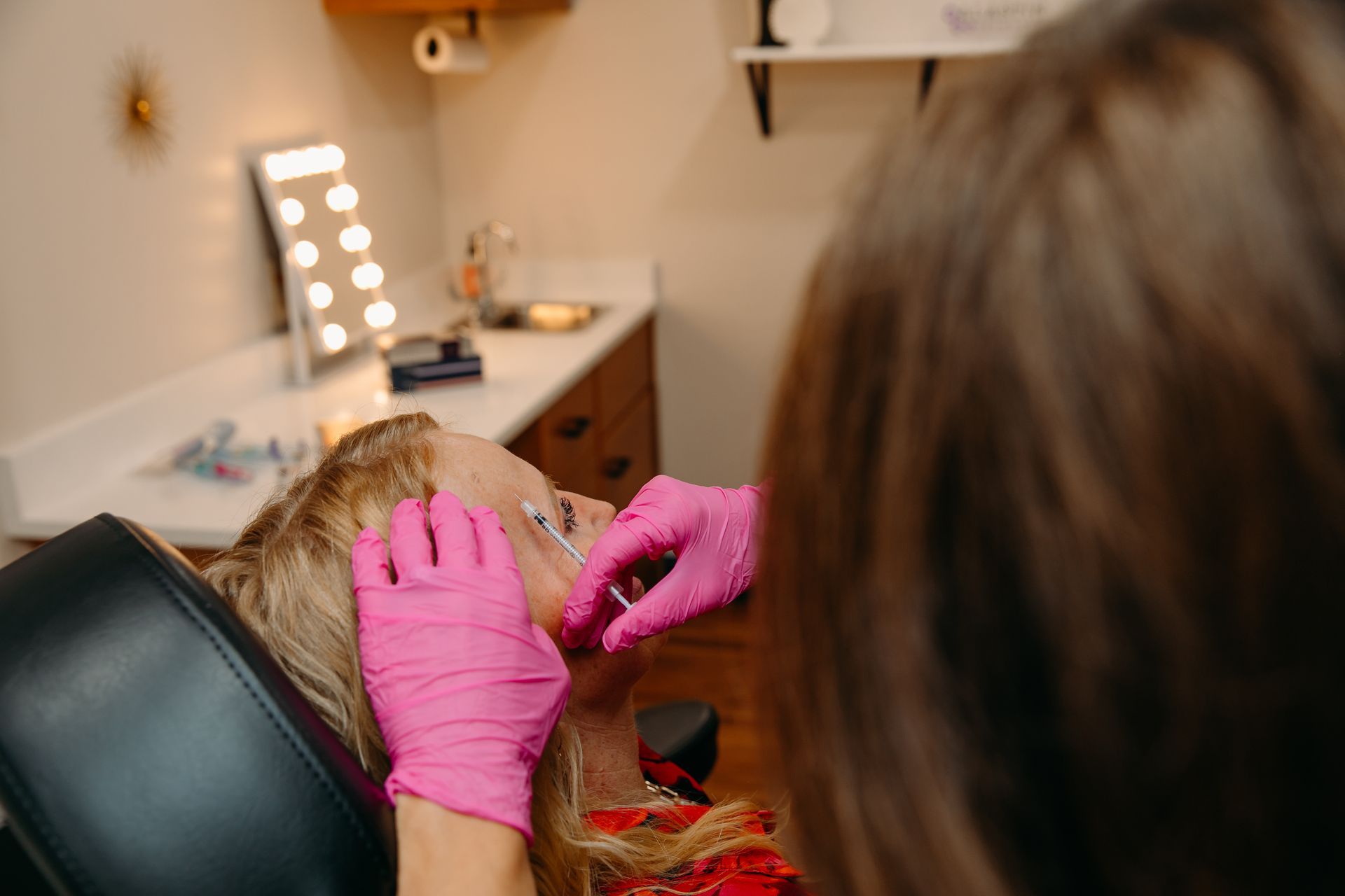 A woman is laying on a bed getting a treatment on her face.