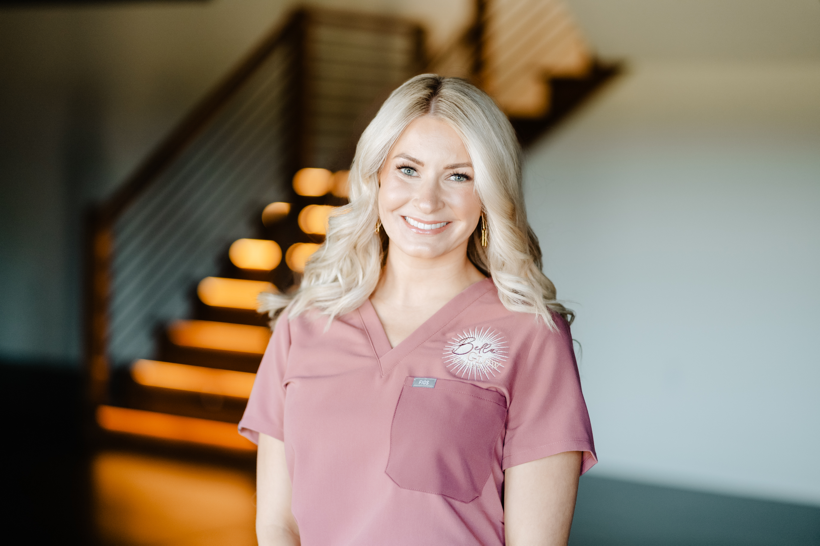 A woman in a white coat is smiling with her arms crossed.