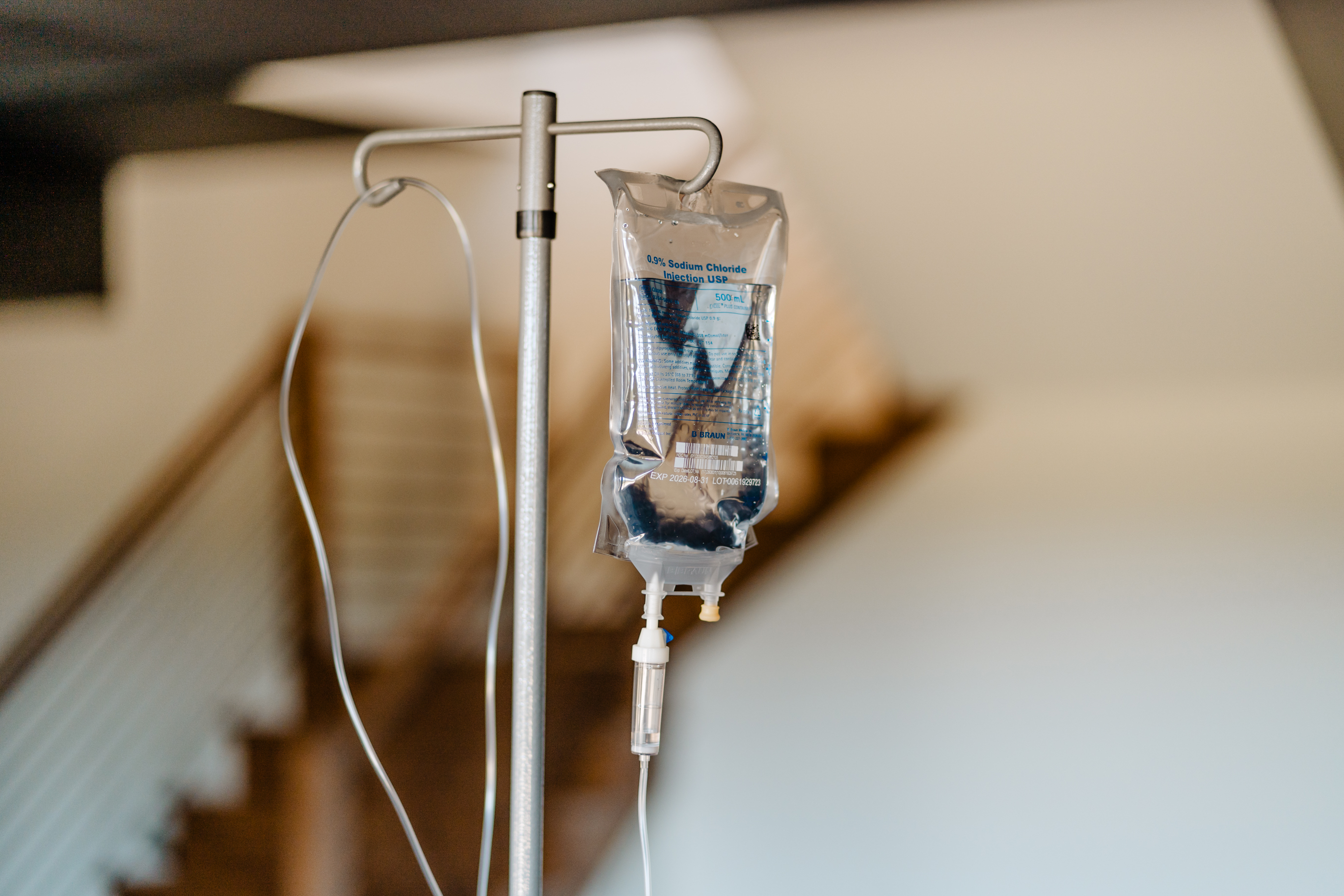 A woman is sitting on a bed with an iv in her hand.