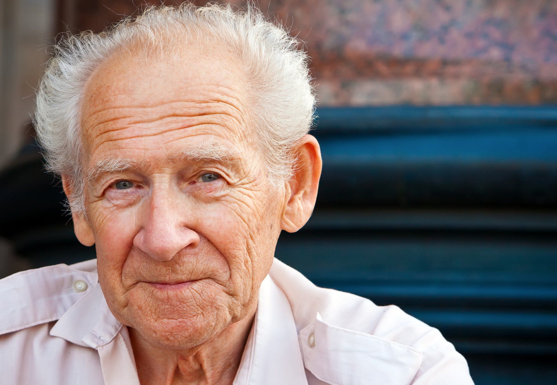 A portrait of an individual with white hair and wrinkled skin, looking directly at the camera with a gentle expression.