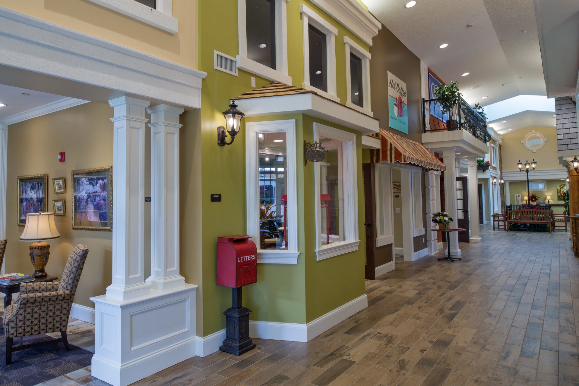 Indoor hallway designed to resemble a charming street with green and cream facades, arched windows, and a red mailbox.