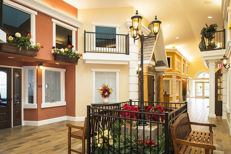 An indoor common area resembling a small town square, with building facades, a street lamp, and a bench in a foyer.