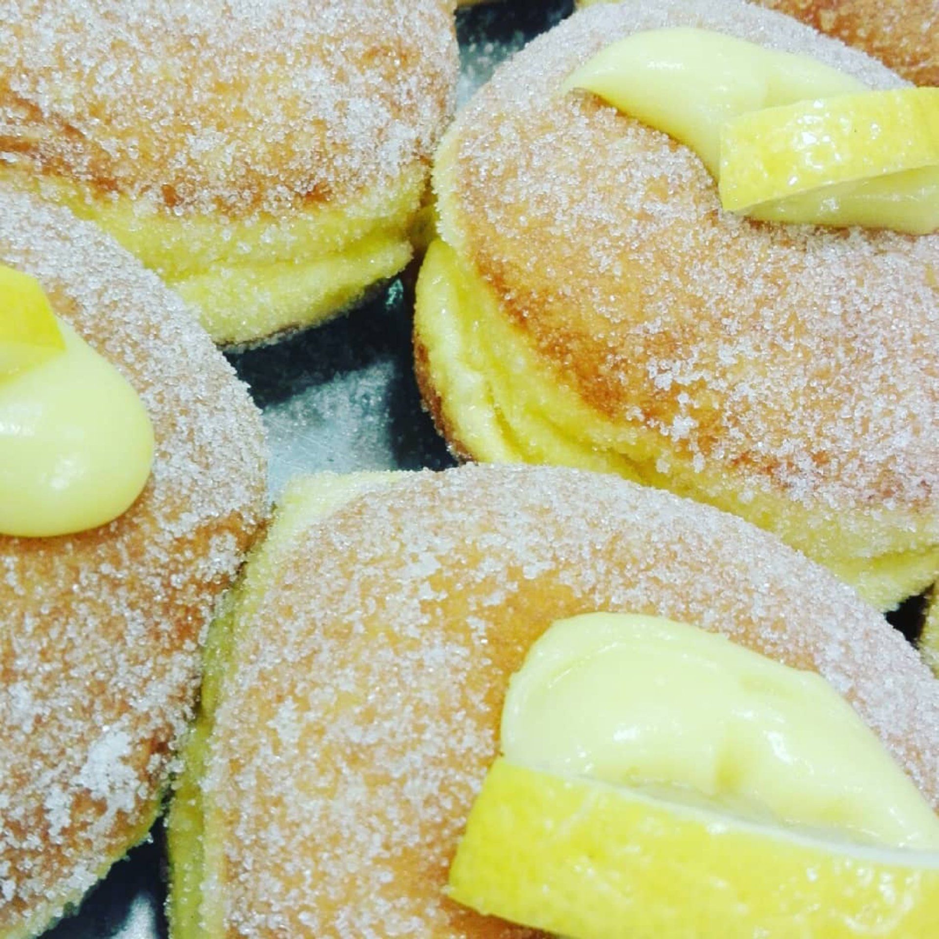 Primo piano di ciambelle zuccherate con ripieno di crema al limone e fette di limone.